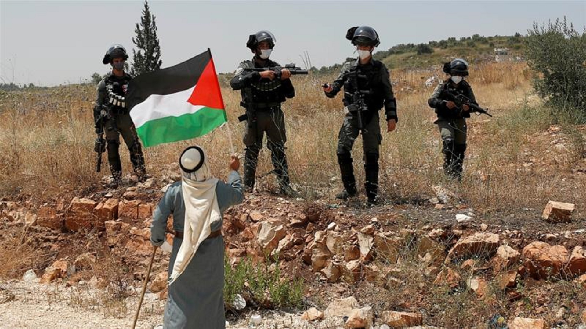 ضفة ثالثة/متظاهر يرفع علم فلسطيني أمام القوات الإسرائيلية (رويترز